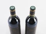 two bottles of wine sitting next to each other on a white surface