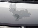 a white car with a dirty paint on it ' s hood