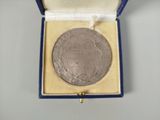 an image of a silver medal in a blue box on a white surface