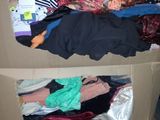 a cardboard box full of clothes and clothes sitting on the floor