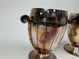 two silver vases sitting next to each other on a table