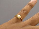 la main d'une femme ornée d'une bague en perle