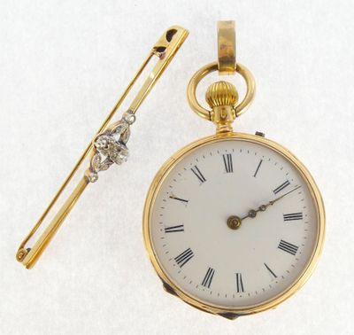 a gold pocket watch and a tie bar on a white surface