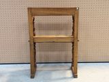 a small wooden chair that is on display in front of a wall