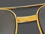 sunglasses with a gold frame and black lenses on a gray background