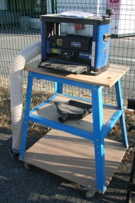 un chariot bleu sur lequel est posé un micro-ondes, à côté d'une clôture