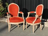 pair of orange velvet upholstered chairs in front of a black wall