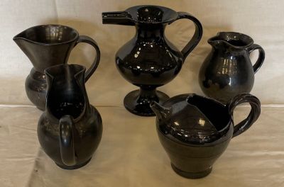 four black vases sitting on a table with a white background