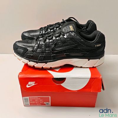 une chaussure de course Nike noire et blanche posée sur une boîte rouge