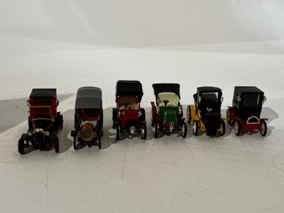 several toy cars are lined up in a row on a white surface