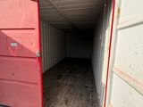 a red storage container with a door open in a parking lot