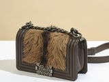 the brown and black fur purse is sitting on a white table