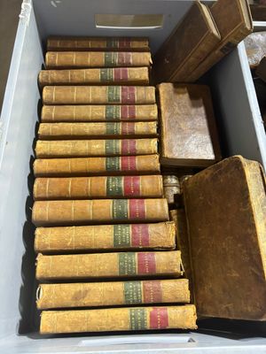 Plusieurs vieux livres se trouvent dans une boîte blanche posée sur une table