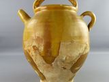 a yellow vase with a handle on a white surface