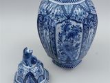 a blue and white vase with a lid next to it