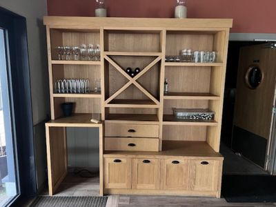 une armoire en bois sur laquelle sont posés un casier à bouteilles et des verres à vin