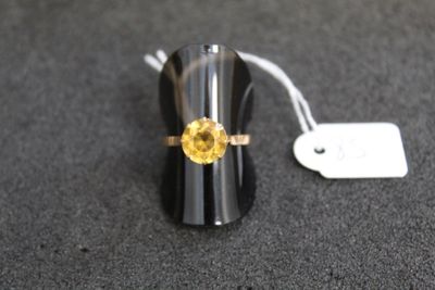 une bague ornée d'une pierre jaune, posée sur une table