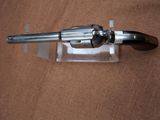 a silver revolver on a clear stand on a brown surface
