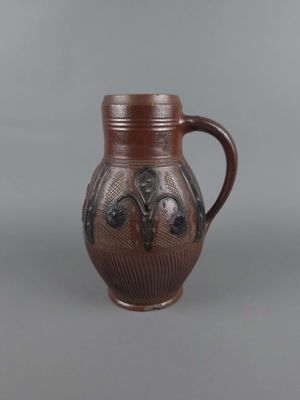 un vase marron muni d'une anse, sur fond gris