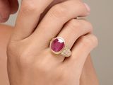 close up of a woman ' s hand holding a ring with a ruby stone