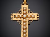 un pendentif en forme de croix en or orné de perles sur fond noir
