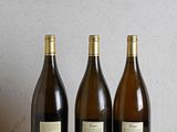 three bottles of wine are lined up on a wooden table
