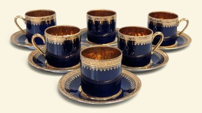 six tasses et soucoupes sont posées sur une soucoupe, sur une surface blanche
