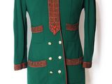 une veste verte avec des bordures rouges et des boutons dorés, présentée sur un mannequin