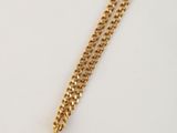 un collier en or avec un pendentif en forme de carré orné d'une pierre, monté sur une chaîne