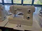 a white sewing machine sitting on a table in front of a window