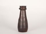 un vase brun posé sur une surface blanche