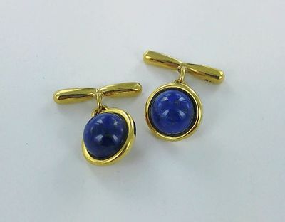 a close up of a pair of blue cufflinks on a white surface