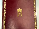un vieux livre rouge aux tranches dorées, orné d'une couronne sur la couverture