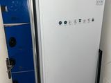 un réfrigérateur blanc dans un coin de la pièce, à côté d'un placard bleu