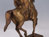 statue of a man riding a horse on a wooden base