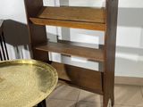 a small table with a gold tray on it next to a book shelf