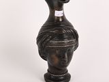 un vase orné d'une tête, posé sur un fond blanc