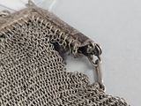 silver chain mail bag with a clasp and chain around the clasp
