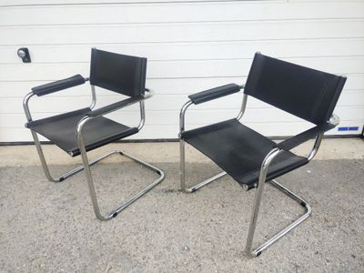 two black chairs sitting next to each other in front of a garage door