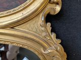 a mirror with a gold frame on a black wall