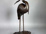 une image représentant une statue en bronze d'une grue posée sur un rocher