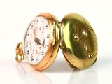 une montre de poche en or posée sur une surface blanche