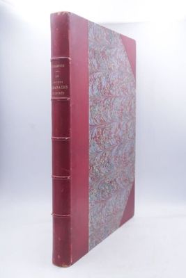 un vieux livre posé sur une surface blanche, avec une couverture rouge