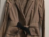 brown jacket with black bow tie on hanger in front of white wall