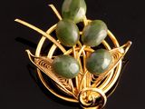 broche plaquée or ornée de jades verts sur un fond noir