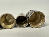 three silver and gold cups sitting next to each other on a white surface