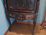 une armoire en bois ornée de sculptures, placée à côté d'un fauteuil à bascule