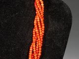 a close up of a necklace with orange beads on a mannequin