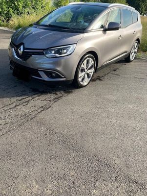 a grey car parked on the side of a road next to a forest