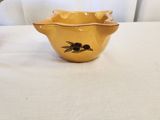 a small yellow bowl sitting on a table next to a vase